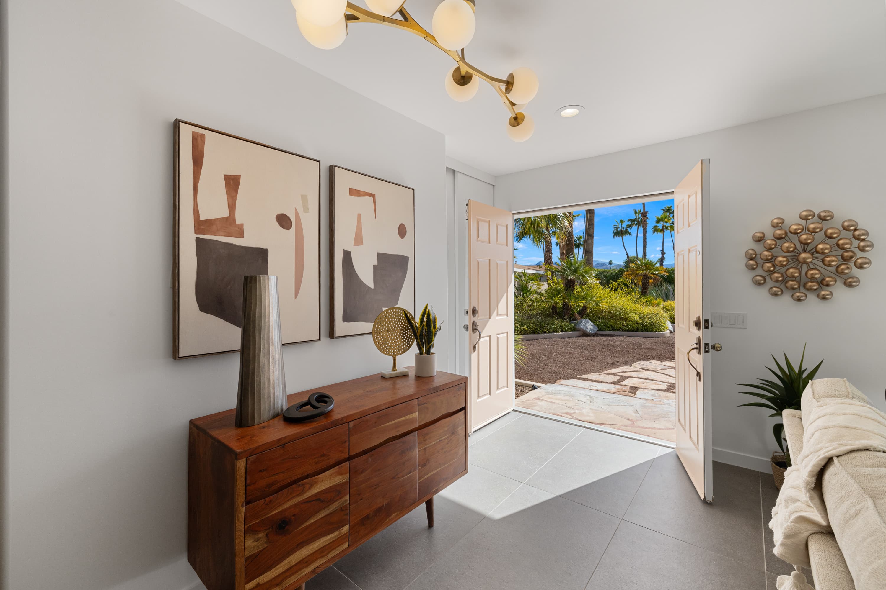 Entry foyer with walnut credenza and doors open to the palms